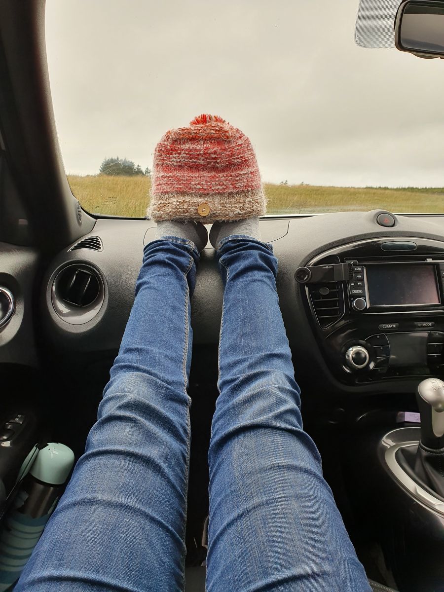 Theresa von Reisekröten, im Auto in Schottland, mit einer Mütze über den Füßen