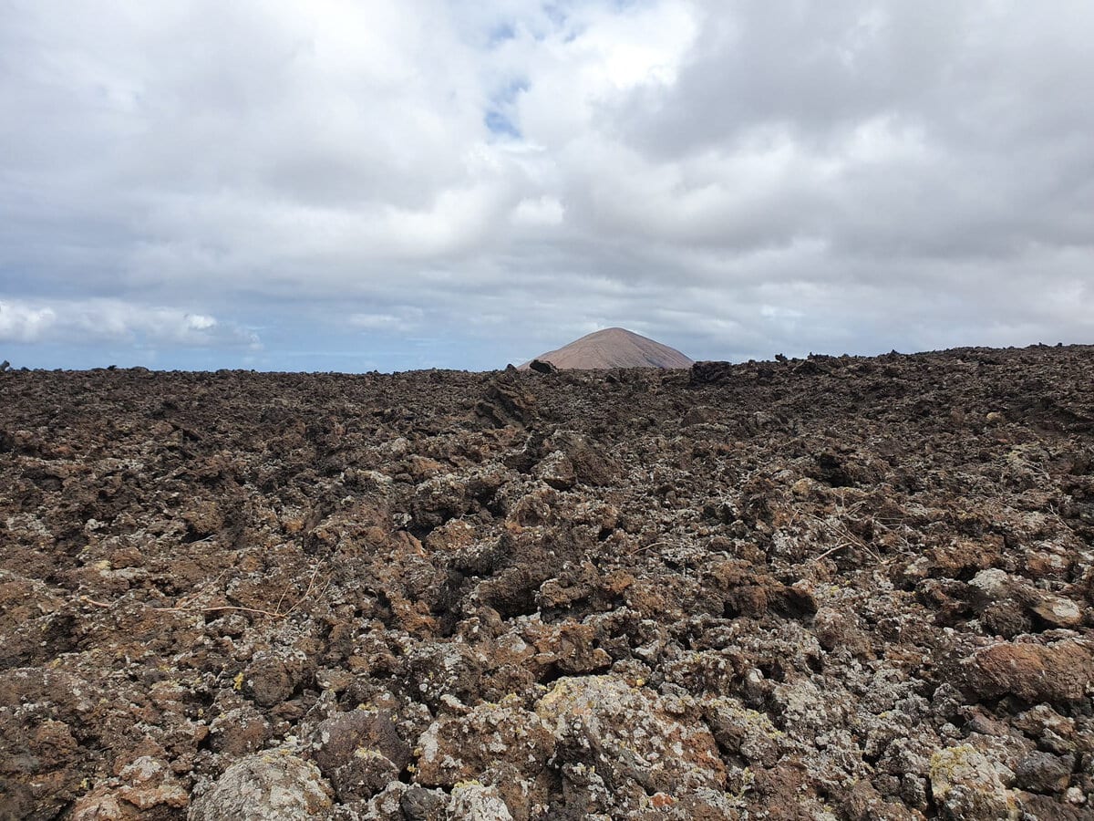 Wanderweg durch das schwarze Lavafeld, im Hintergrund der helle Kegel der Caldera Blanca