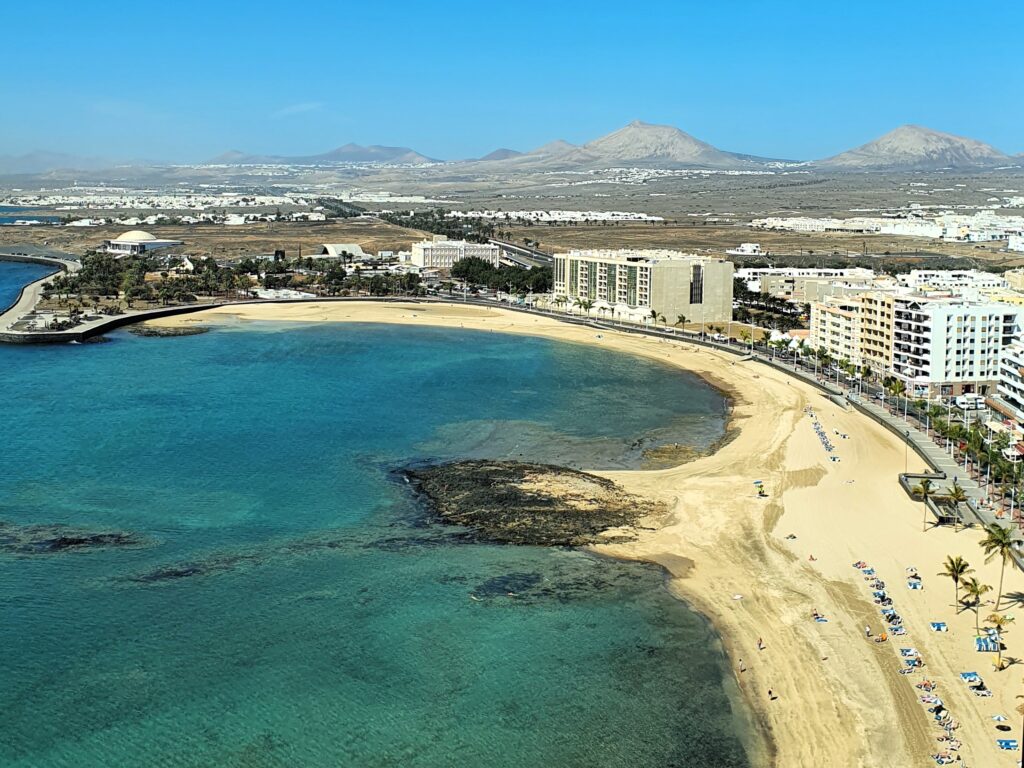 Panorama des Playa Reducto mit den Vulkankegeln von Lanzarote im Hintergrund