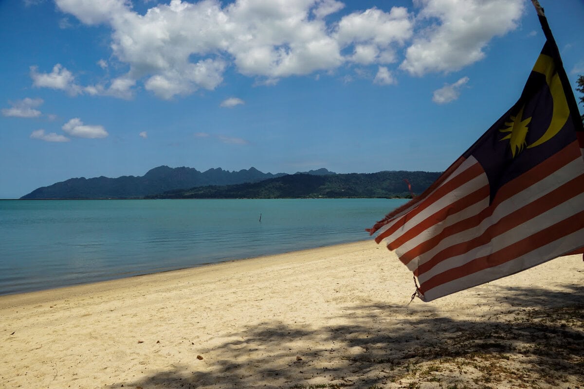 Die beste Reisezeit für Langkawi zwischen November und März - Flagge Malaysia auf Strand in Langkawi