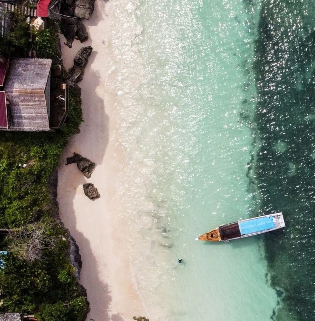Küste von Bira auf Sulawesi mit klarem Wasser zum Schnorcheln und Tauchen sowie Tauchboot am Strand