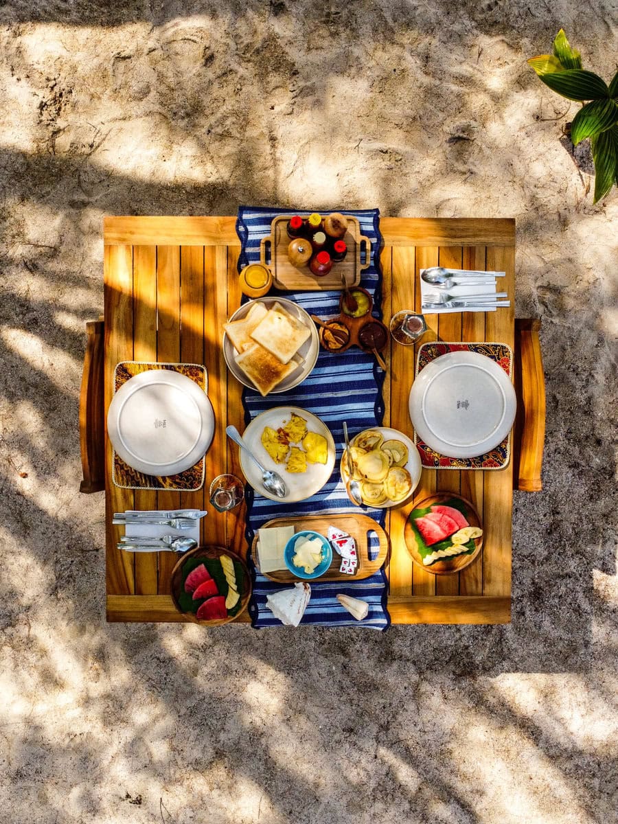 Flatlay eines Frühstückstisches im Sand auf Saronde Island in Indonesien