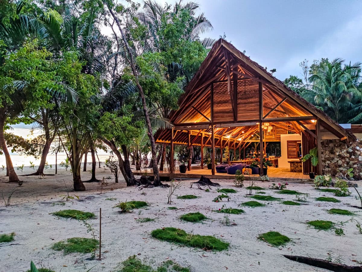 Beleuchtetes Restaurant ohne Außenwände erbaut aus Holz am Strand von Saronde Island in Sulawesi