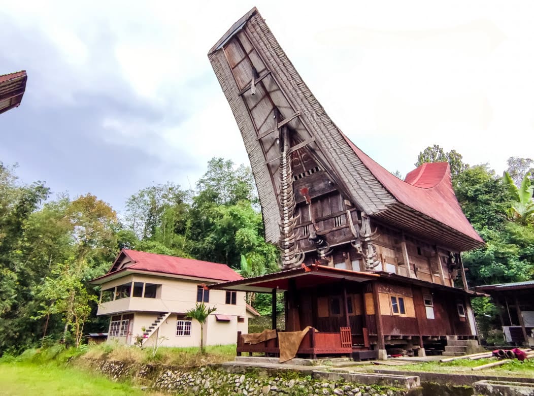 Traditionelles Tongkonan Haus in Toraja neben modernem Haus