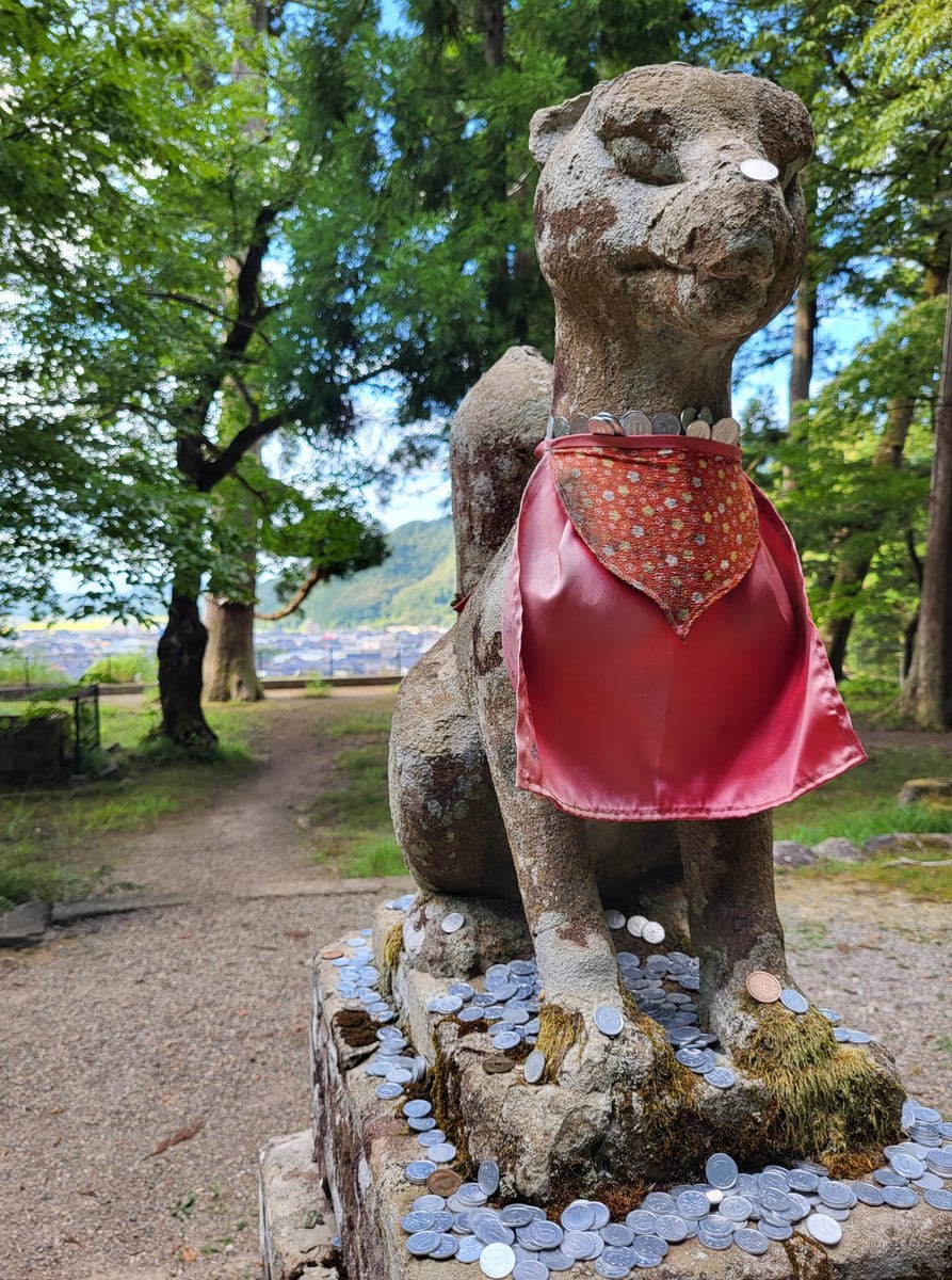 Wächterfigur vor einem japanischen Tempel mit Geld rundherum