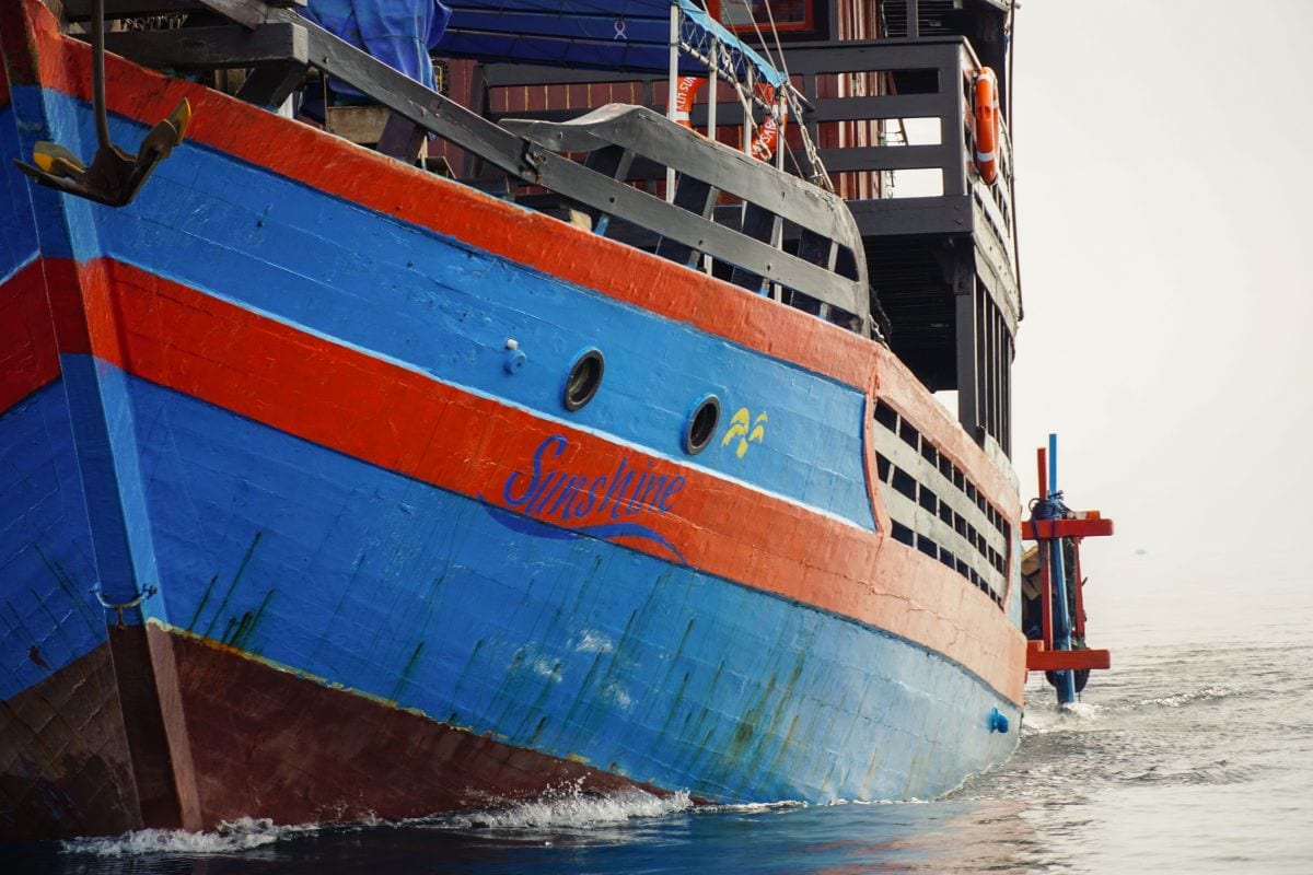Tauchsafari KLM Sunshine Nahaufnahme des orange-blau-farbenen Pinisi Holzschiffs in Sulawesi