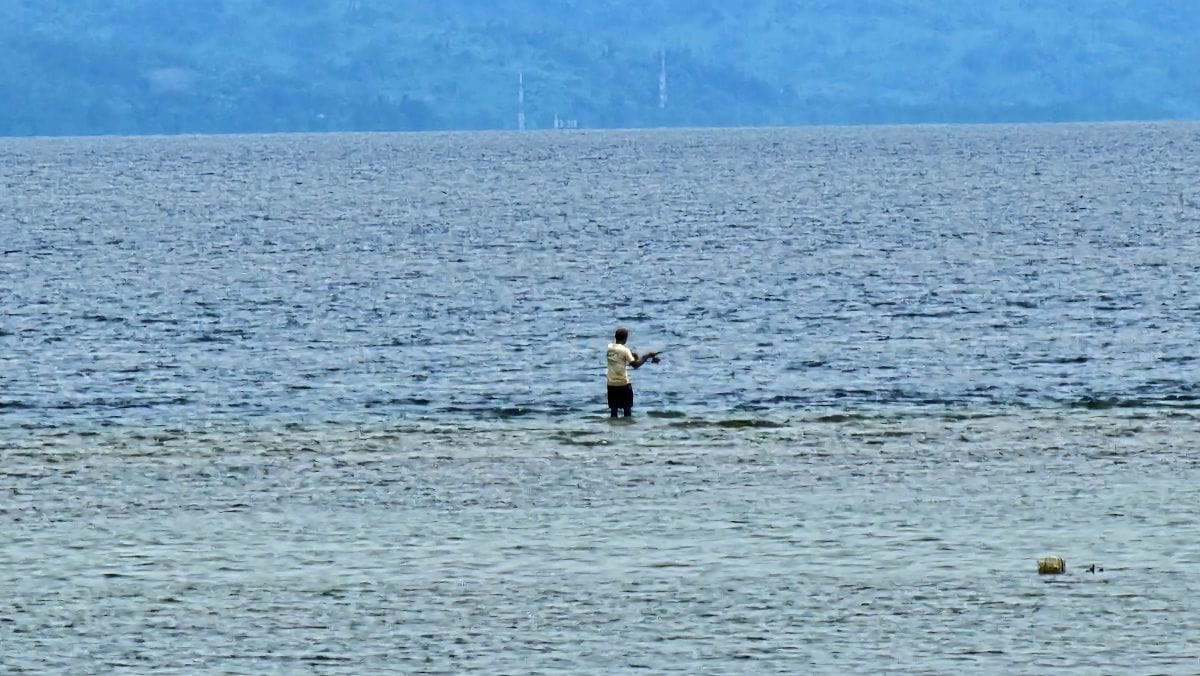 Lokaler Angler auf Bunaken, der auf den Korallen steht