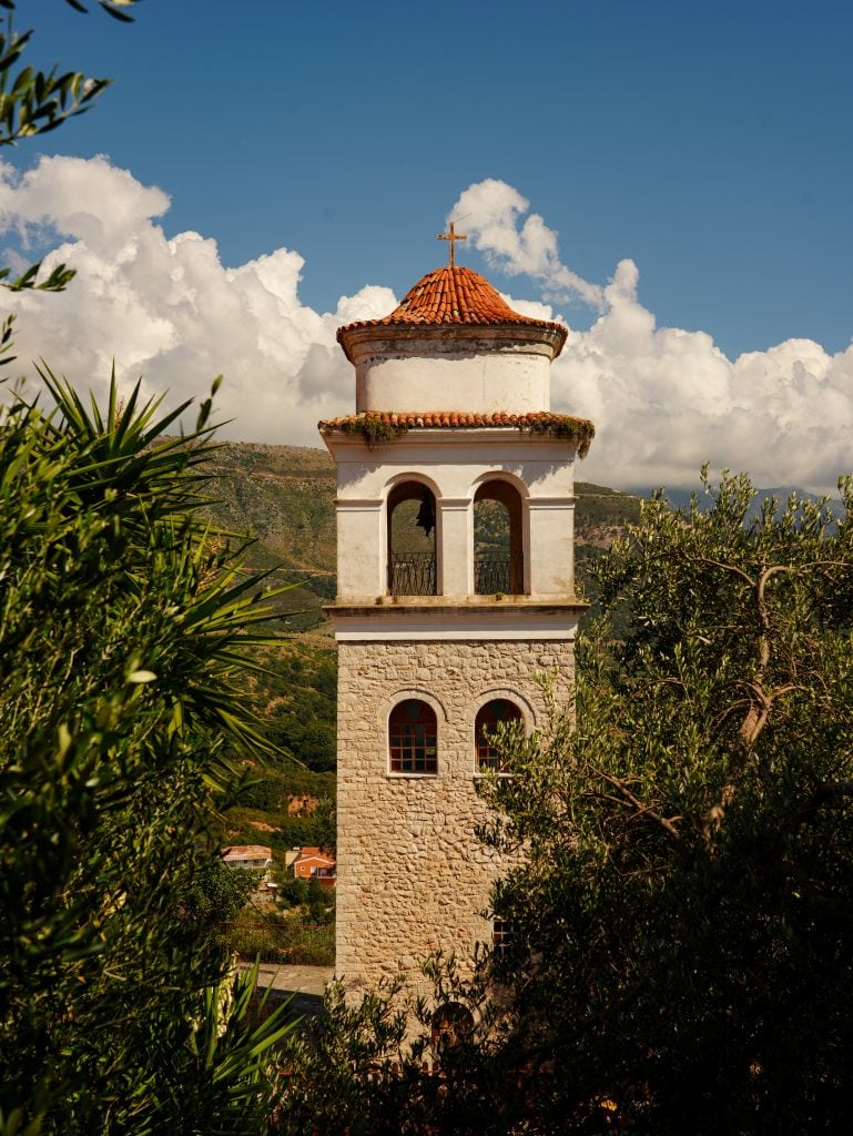Turm einer historischen Kirche in Himaras Altstadt vor blauem Himmel.
