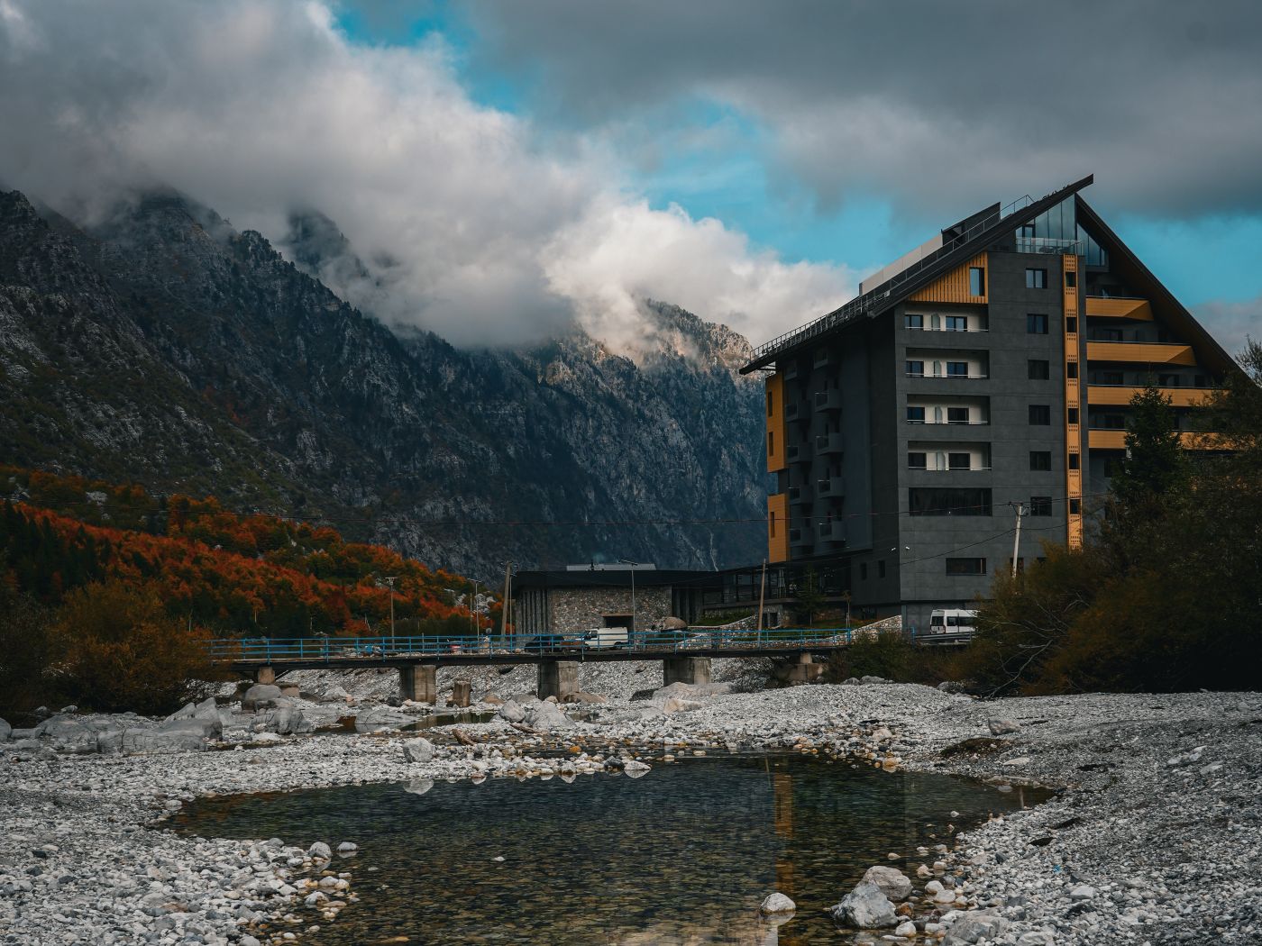 Hotel im Tal von Valbona mit Bergen im Hintergrung und Fluss im Vordergrund