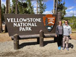 Yellowstone Reisebericht: Chris und Theresa von Reisekröten am Schild des Yellowstone Nationalparks