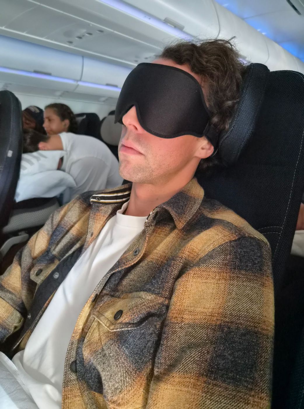 Chris von Reisekröten mit 3D-Schlafmaske im Flugzeug