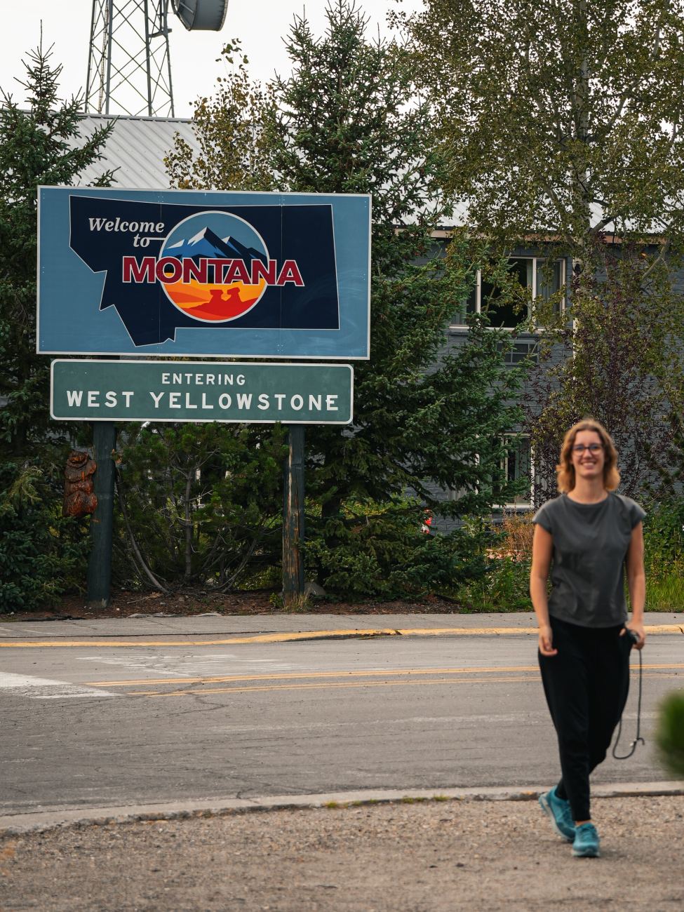 Theresa von Reisekröten vor dem Ortsschild von West Yellowstone in Montana, USA